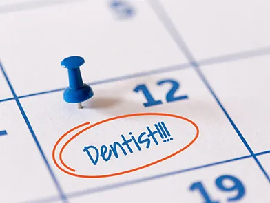 A calendar with a blue pushpin marking a dentist appointment.